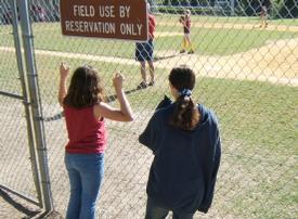 Youth softball players learn from older players.